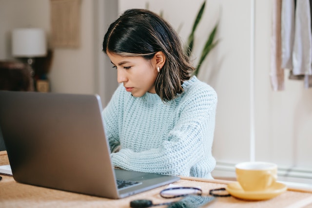 Eine Frau arbeitet beim Online-Coworking am Laptop. Daneben steht ihr Kaffee .